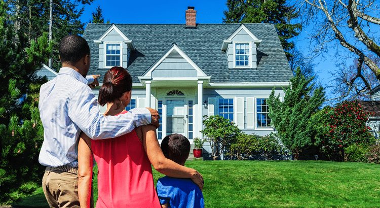 Husband, wife, and child standing in front their new home.