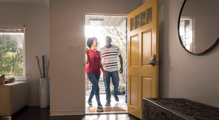African-American couple standing at the doorway of their home with the door open